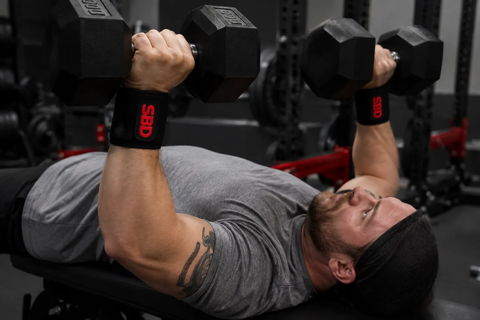 Flexible SBD wrist wraps used during dumbbell pressing in a strength gym